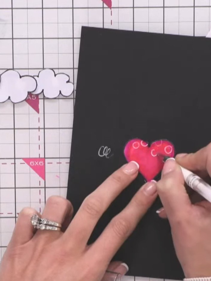 Step 7: Using a white gel pen, draw small circles on the pink heart balloon to add decorative detail and dimension.