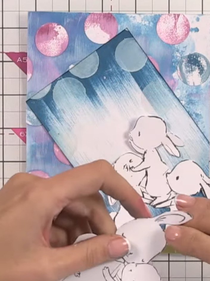 Step 12: Arrange and glue the fussy-cut bunnies onto the card in a cuddling position, placing the largest bunny at the 