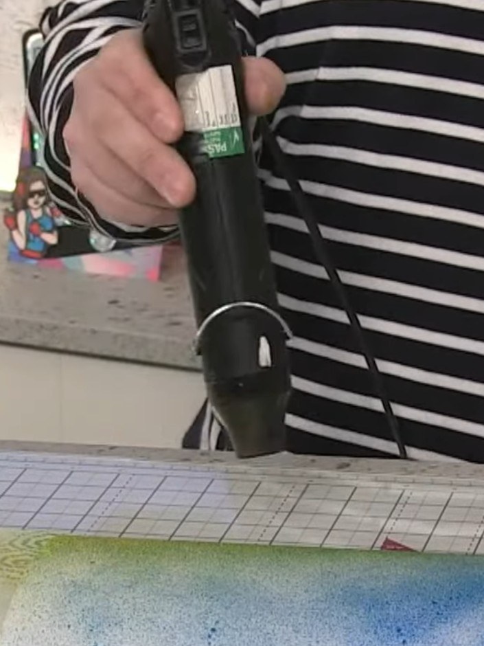 Step 3: Use a heat gun to dry the sprayed inks on the card, moving it over the surface to set the colours completely.