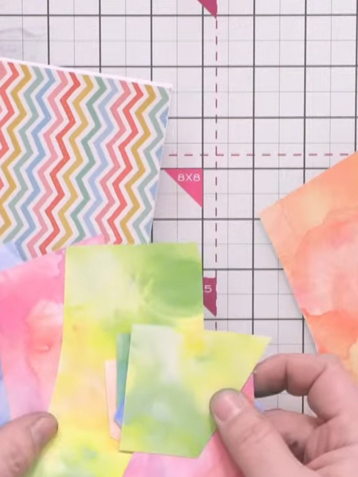 Step 3: Arrange small scraps of coloured card and watercolour paper onto the black base card in a pleasing layout. Use