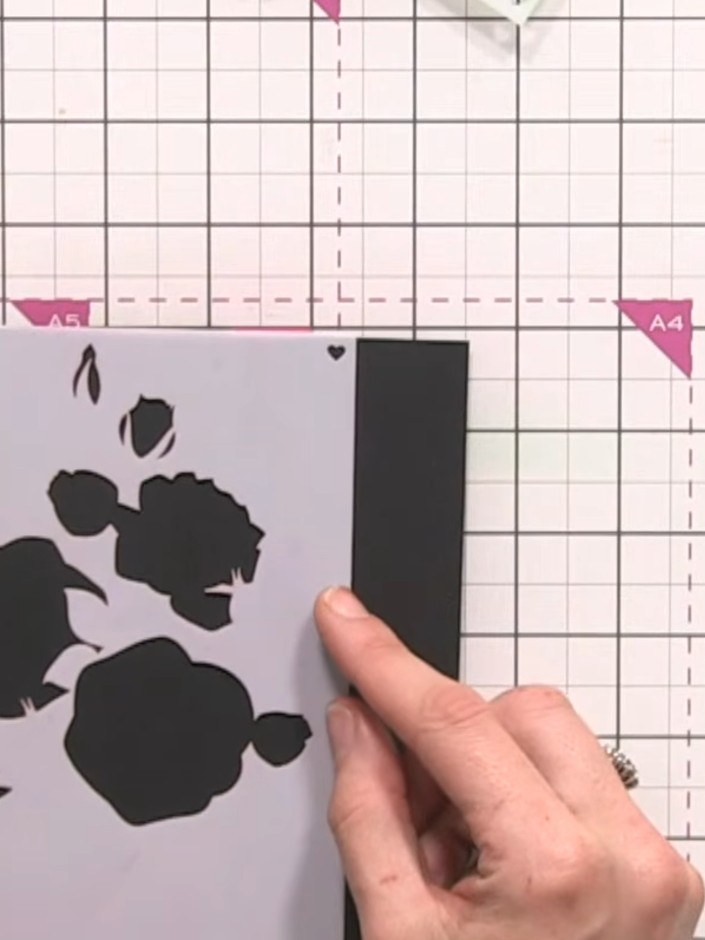 Step 2: Position the rose branch stencil on the black card, aligning it at the edge. Ensure the stencil is held firmly