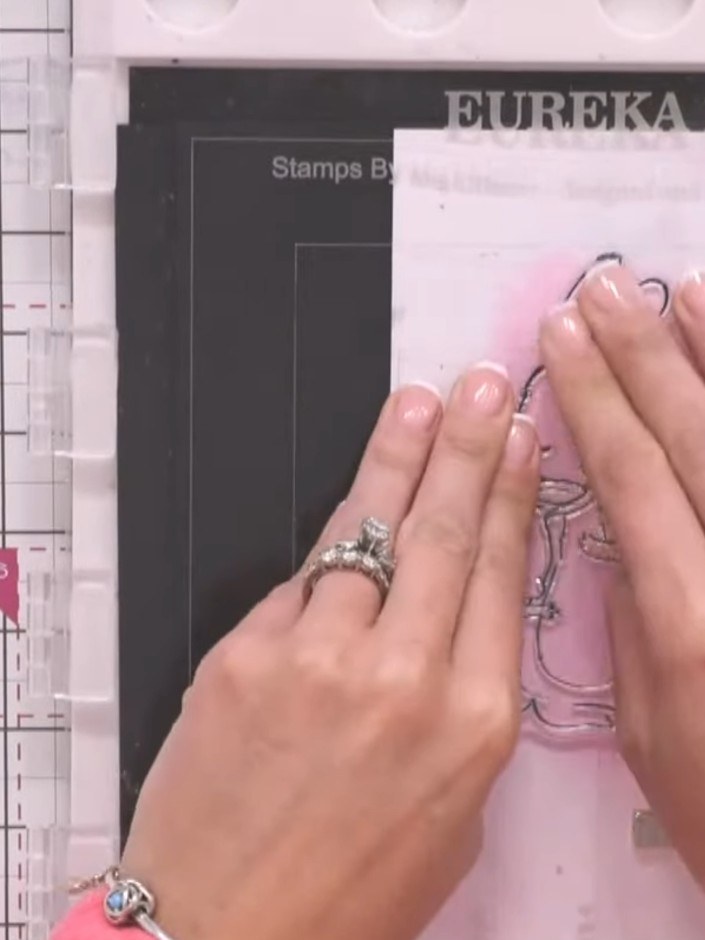 Step 10: Stamp the bunny family image onto the dried watercolour background using pink ink. Position the stamp centrall