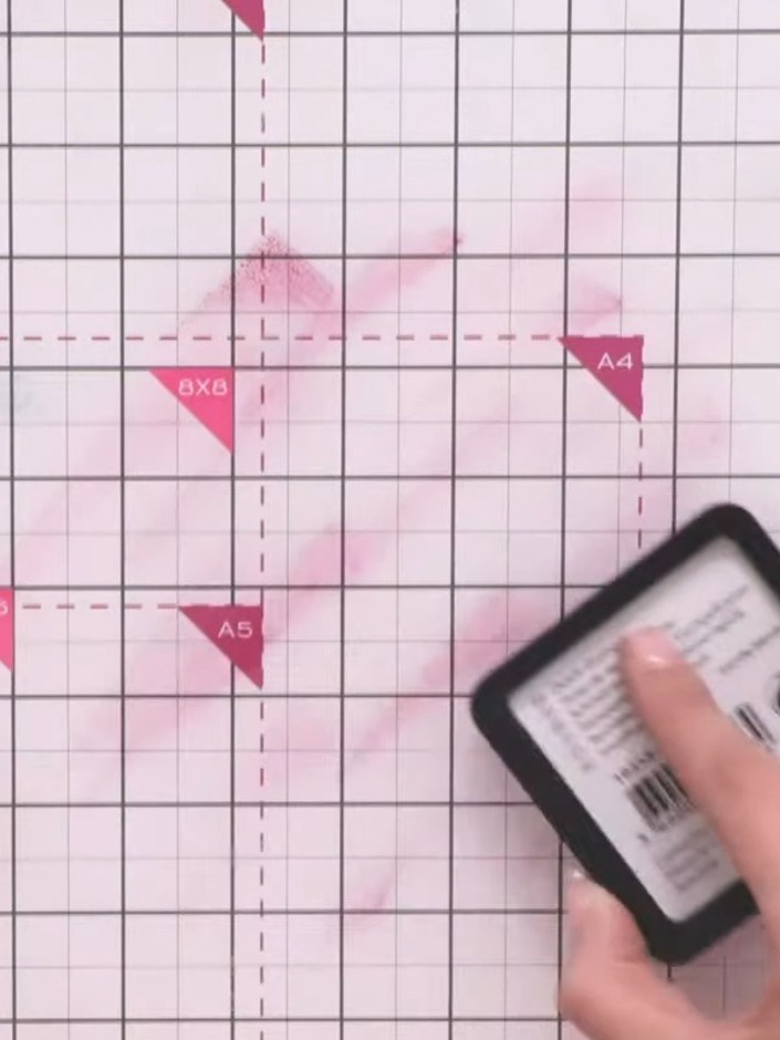 Step 6: Create a coloured base layer by dropping pink ink onto your craft mat, spraying with water, and swishing with 