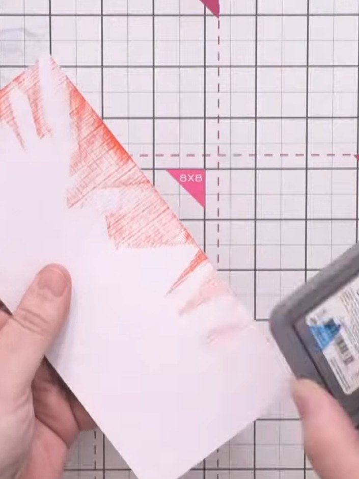 Step 2: Using a distress oxide red ink pad and a cloth, lightly brush the red ink across the card surface to catch the