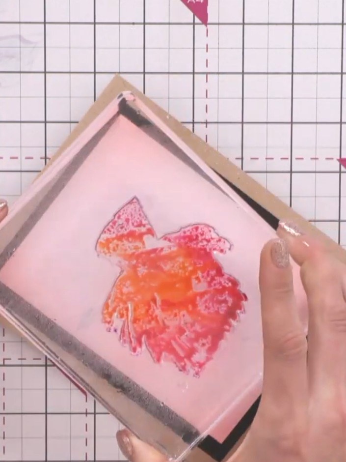 Step 1: Take the solid portion of the lamination stamp and apply colour to it using orange and red ink sprays. Spray t