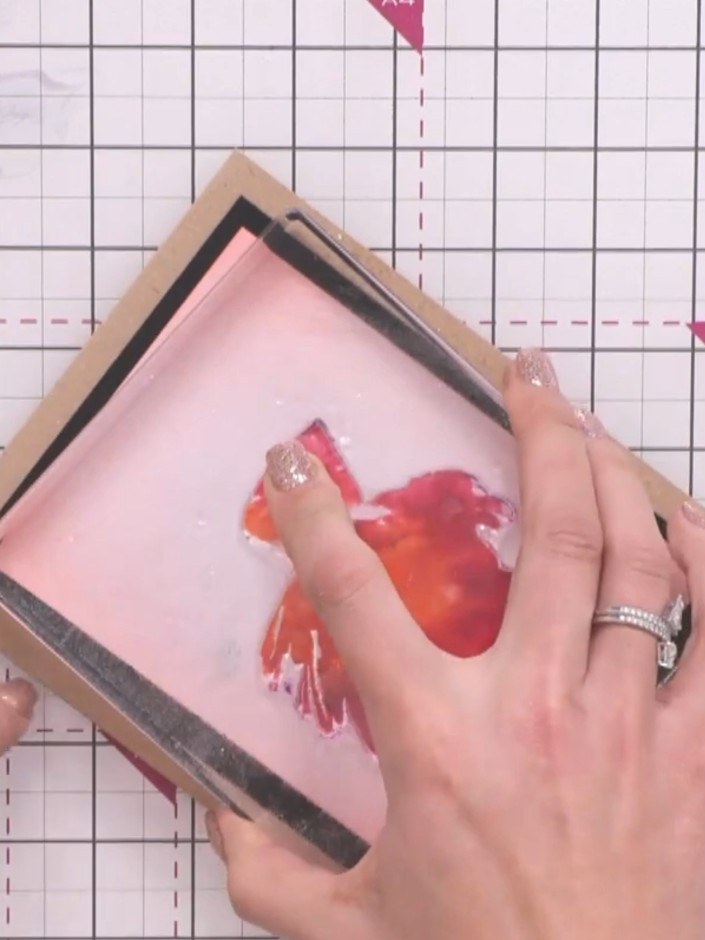 Step 3: Press the stamp firmly onto the pink cardstock and hold it down to allow the cardstock to absorb the ink thoro