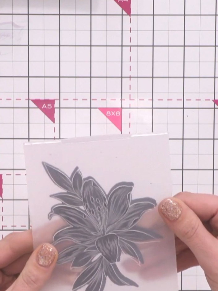 Step 2: Line up the cut black floral embellishment with the embossing folder, ensuring it is oriented correctly. The f