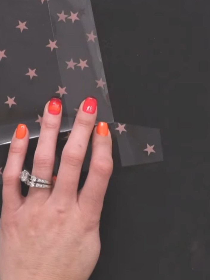 Step 6: Apply double-sided tape to the flaps of the acetate sheet. Fold the acetate up along the score lines, tucking 