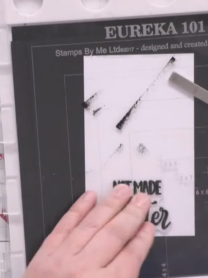 Step 7: Stamp a Christmas sentiment onto a white piece of card using Versafine black ink, positioning it at the bottom
