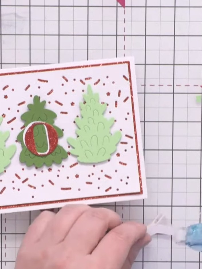 Step 11: Position the white 'Joy' sentiment slightly offset towards the top and left of the red glitter 'Joy' layer to 