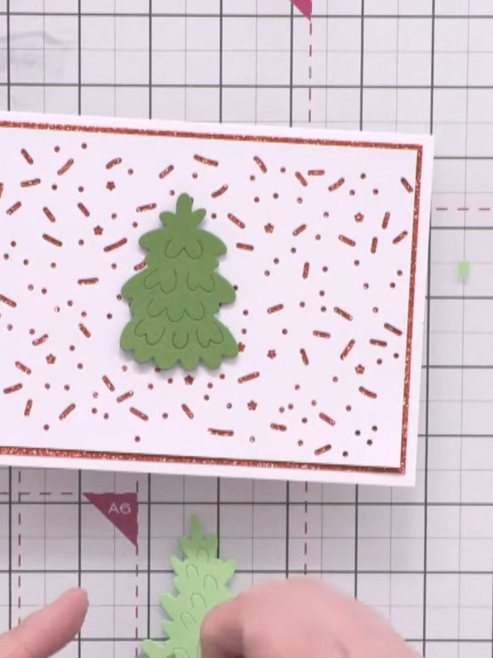Step 8: Attach the dark green tree in the centre of the card using foam pads. Position the two lighter green trees on 