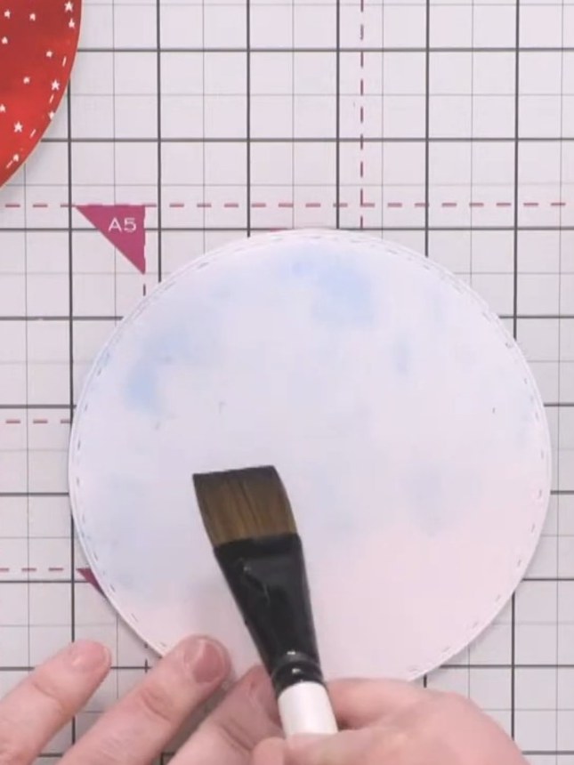 Step 12: Apply water across the top portion of the white circular background using a brush. Add blue watercolour pigmen