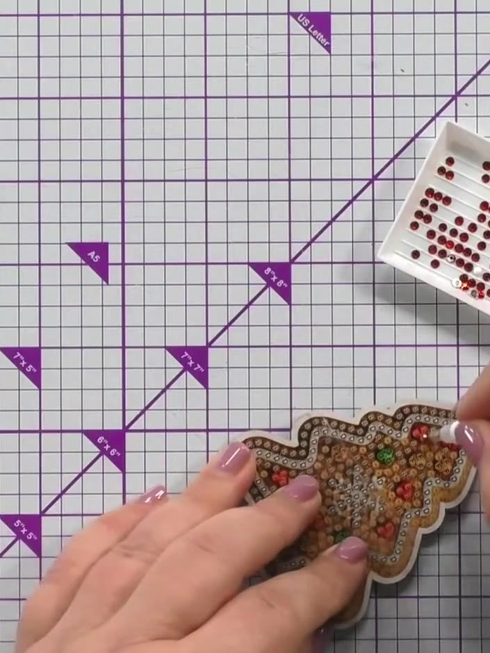 Step 7: Lightly tap each crystal onto the glue at the matching positions on the gingerbread tree decoration, working o
