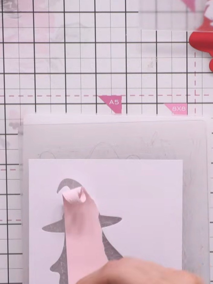 Step 5: Layer the white cloth piece and pink hat belt detail onto the pink ghost outline using adhesive. Position the 