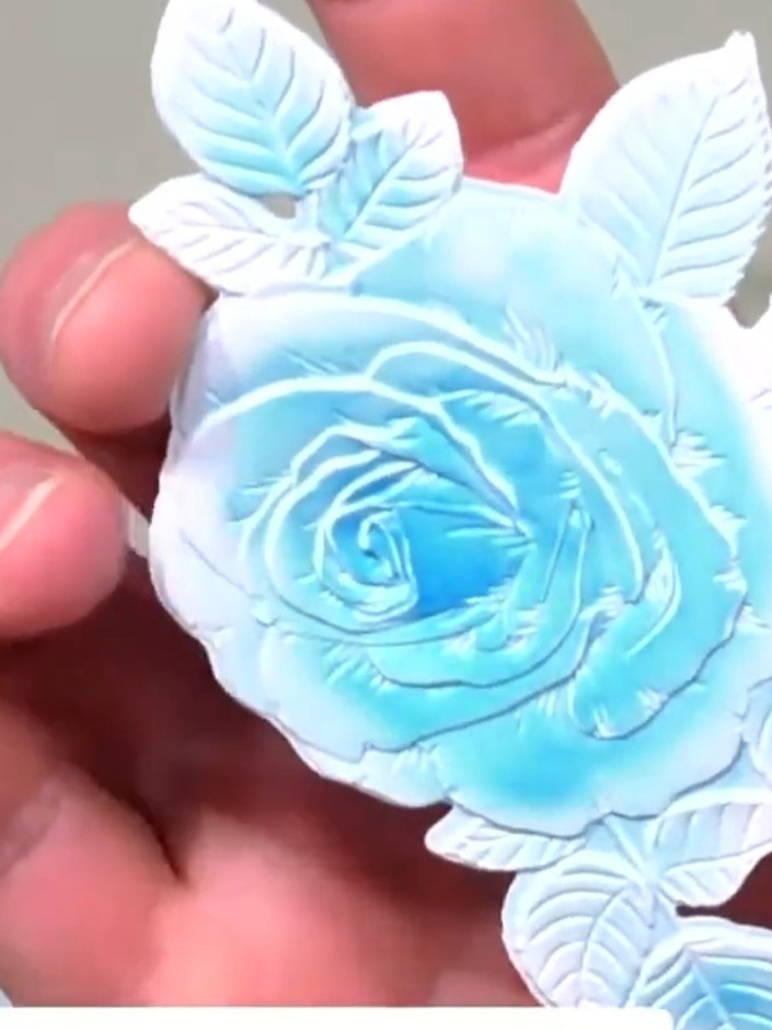 Stap 8: Layer the stamped leaves around the embossed rose on your card base, positioning them to create a pleasing arr
