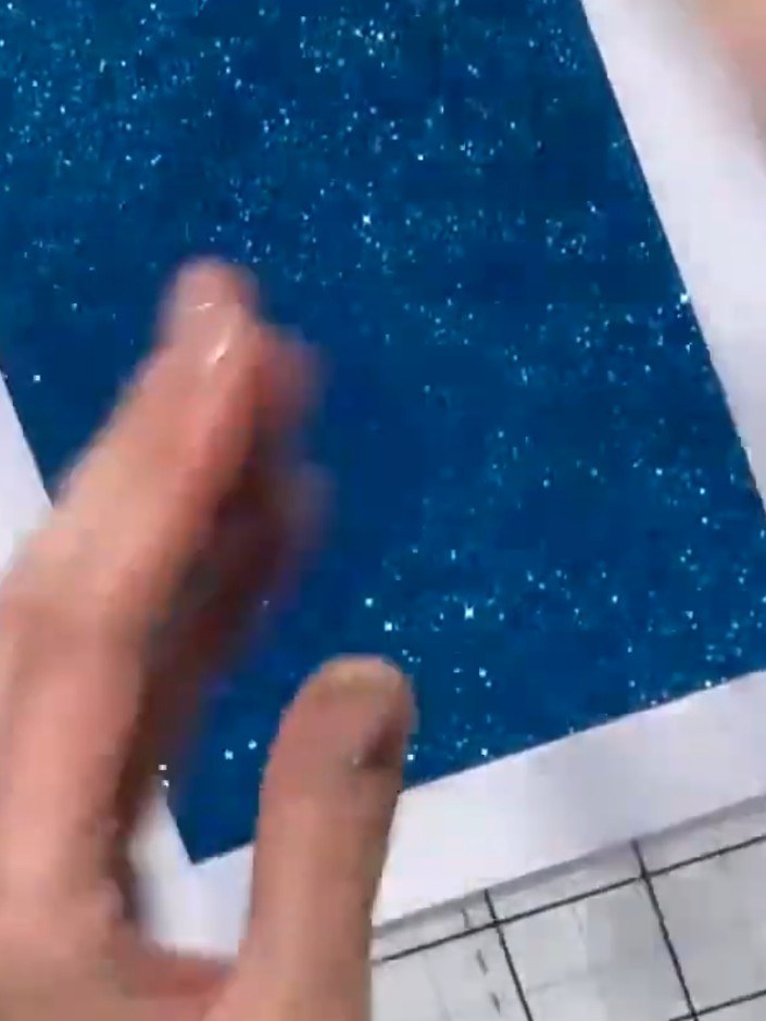 Step 2: Apply adhesive to the back of the sparkly teal textured panel and attach it to the white card base, positionin