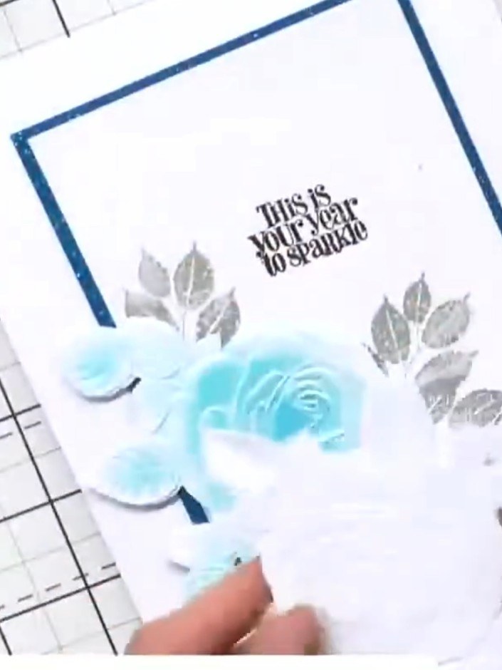 Step 4: Position the embossed rose in the centre of the card front. Add the silver embossed leaves on either side of t