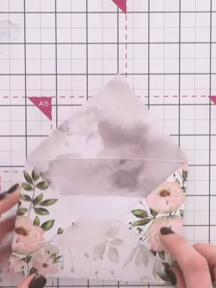 Step 1: Score along the pre-marked lines on the envelope using a scoring tool or bone folder. The envelope has floral 