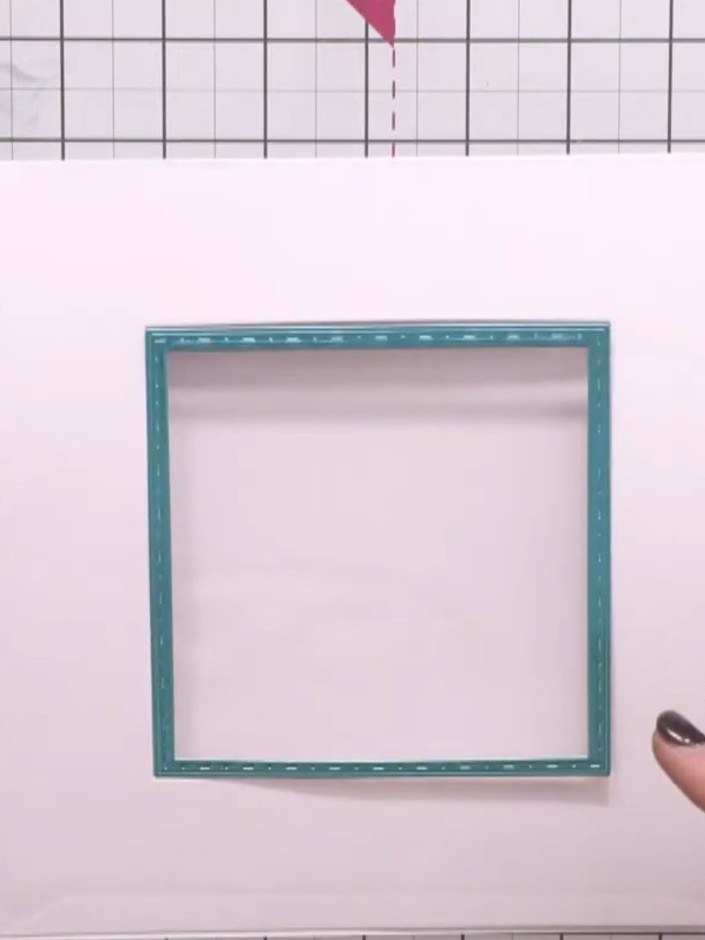 Passo 11: Position the teal mirror board frame over the window recess on the front of the card and glue it in place, ens