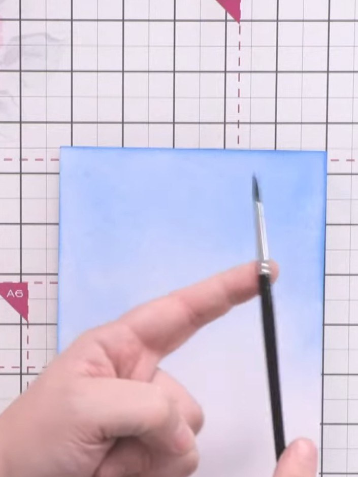 Passo 2: Apply water to the distressed oxide ink using a round brush to create reactive effects. Lift off excess colour