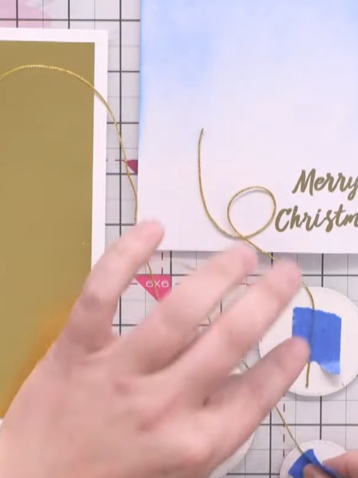 Passo 7: Attach the bauble circles to the card front using foam pads to create dimension. Layer them over the gold wire