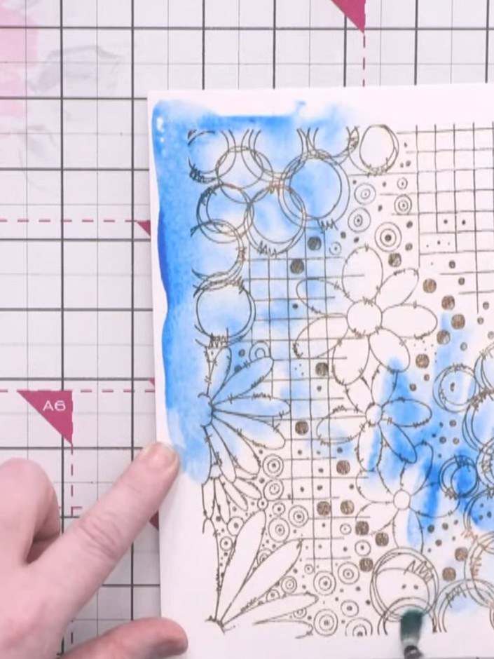 Passo 3: Drop blue watercolour paint onto the wet surface, allowing the pigment to spread naturally across the stamped 