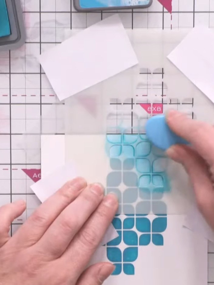 Passo 4: Apply distress ink through the stencil using a blending tool or sponge, working the blue ink over the geometri