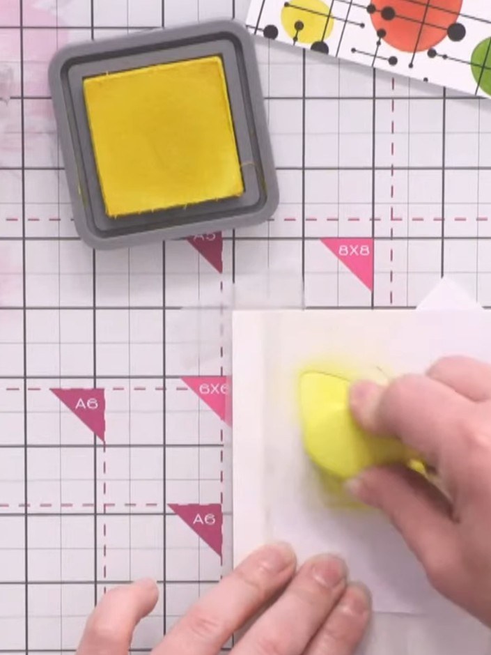 Stap 2: Apply yellow distress oxide ink through the first triangular shape in the stencil using a sponge dauber. Dab t
