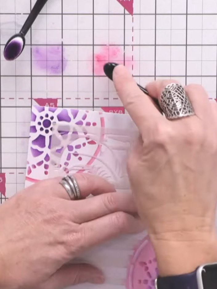 Passo 10: Layer all your decorated elements together, mounting the watercolour stencilled panel onto your card base. Use