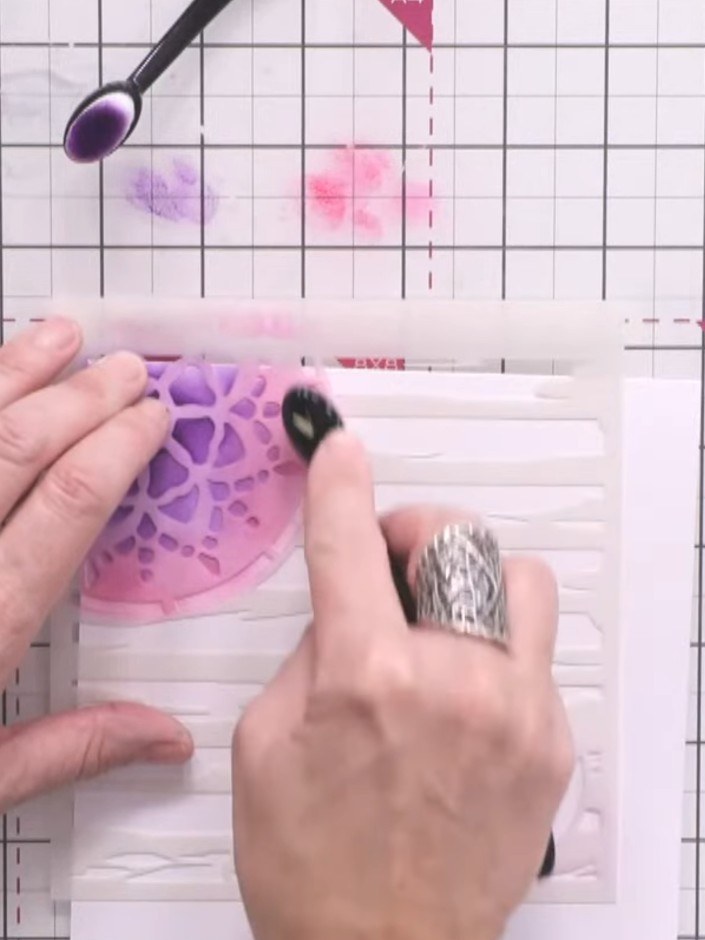 Passo 5: Carefully remove the purple stencil from the card to reveal the blended pink and purple watercolour background