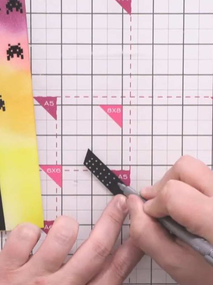 Passo 9: Use a silver pen to draw window patterns on each black building strip. Vary the designs with dots, dashes, lin