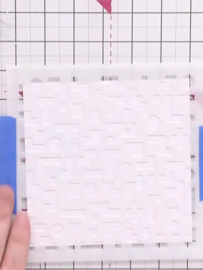 Paso 2: Position the large retro stencil onto your white card base. Secure it in place using blue masking tape at the 