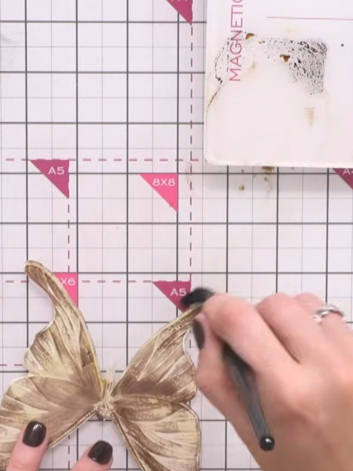Passo 7: Layer darker brown and black tones over the butterfly wings using a fine brush, building depth and dimension w