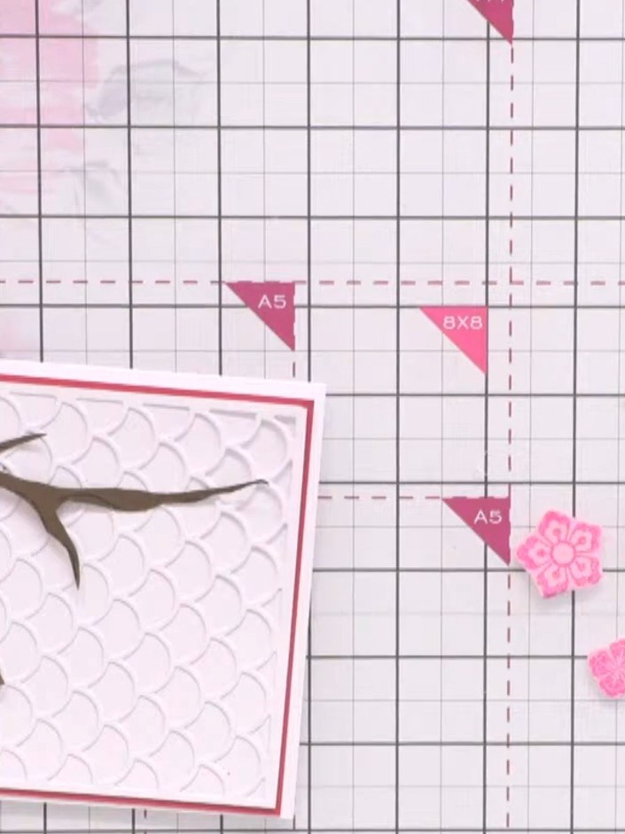 Passo 14: Glue the cut-out pink flowers onto the card in clusters along the branch, varying the shades of pink. Add the 