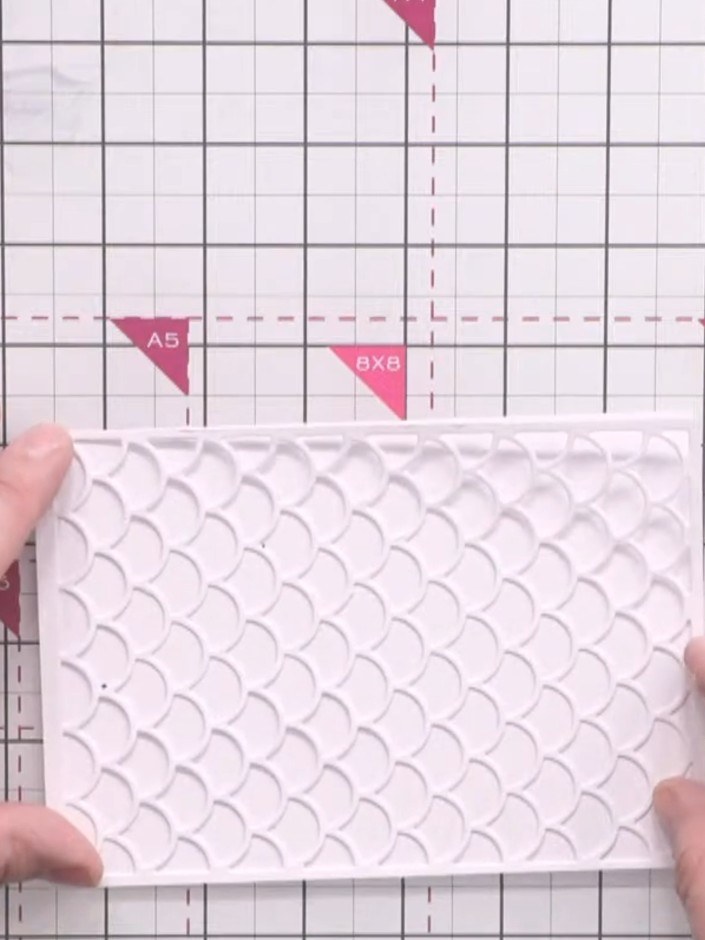 Passo 6: Mount the white scalloped panel onto a deep pink card base to create a vibrant border around the decorative pa