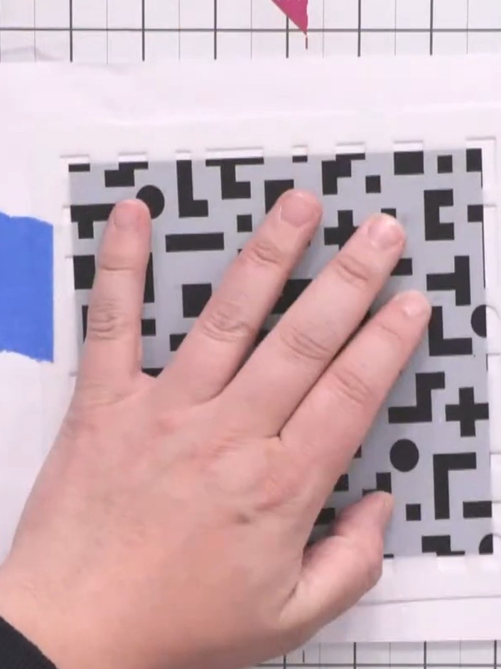 Step 2: Position the pixel pattern stencil over your white card base and secure it in place using blue masking tape on