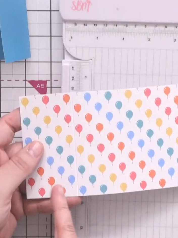 Step 8: Create diagonal score lines across the corners of the white strip to form a cross pattern. Position the strip 
