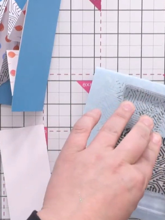 Step 2: Stamp the light blue panels with a background stamp using black ink to create visual interest. Use a geometric