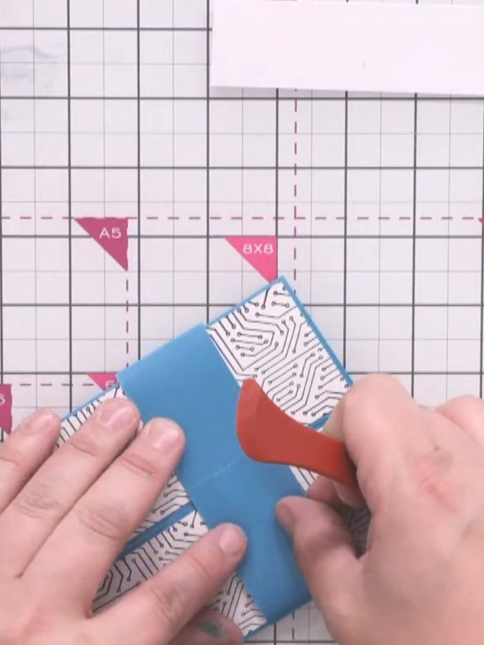 Step 6: Wrap the blue belly band around the closed card and fold it to overlap slightly. Secure the overlap with tape 