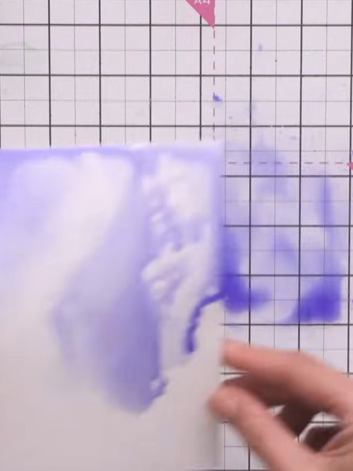 Step 6: Twist and tilt the card to move the purple paint around, creating varied watercolour effects across the surfac