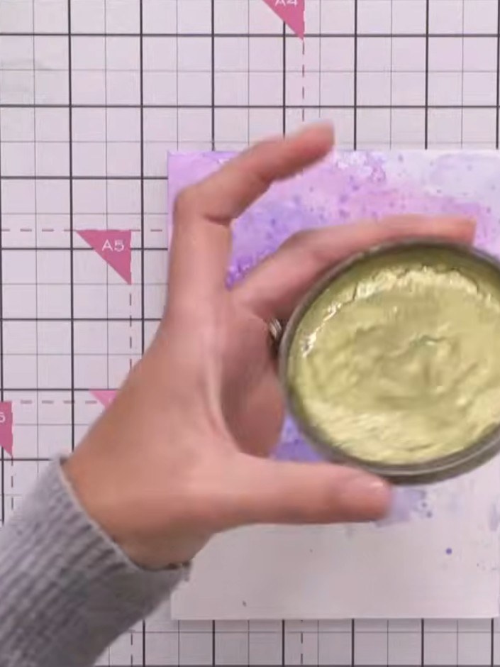 Step 9: Apply a small amount of gold metallic paint to the centre of the purple watercolour background using a paintbr