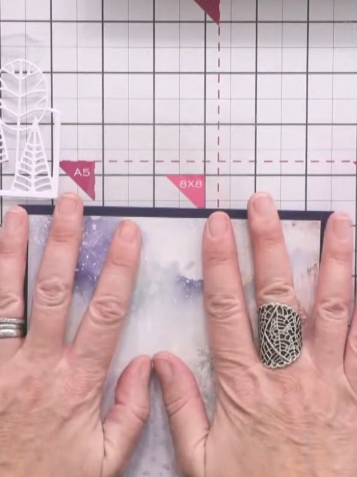 Step 2: Adhere the first patterned paper from the White Magic paper pad to a blue card base as your foundation layer. 