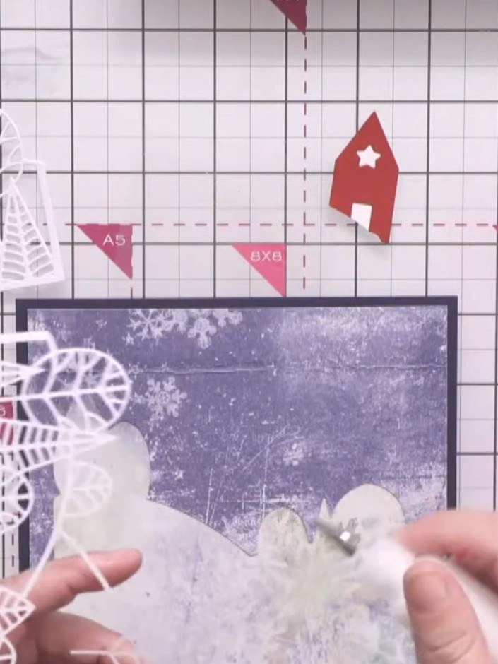 Step 8: Adhere the white line art country view die-cut on top of the blue aperture panel to create dimension and a lay