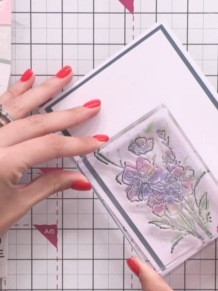 Step 11: Position the clear flower stamp over the watercoloured image on your card panel. Stamp the outline design to a