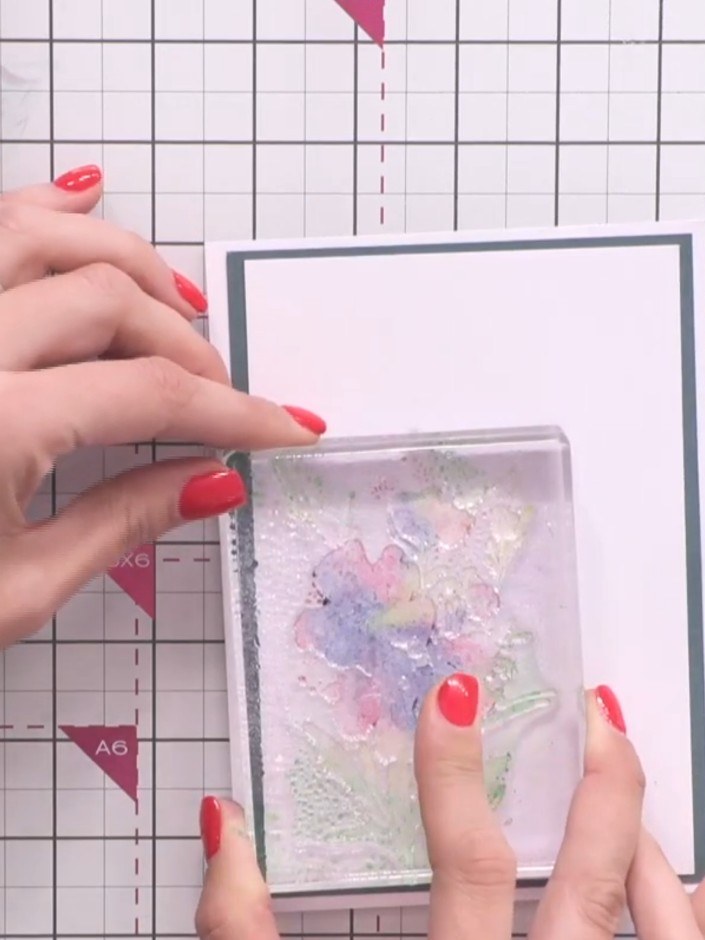 Step 8: Press the stamp down firmly onto the grey bordered cardstock panel to transfer the watercolour effect. Apply e