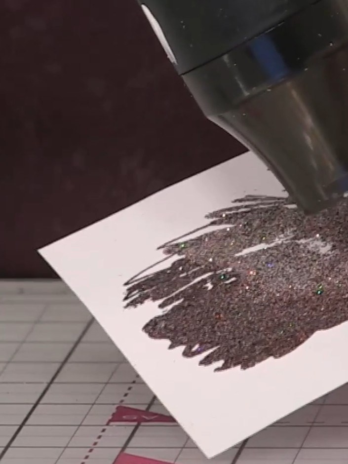 Step 8: Heat set the embossing powder on the dress area using a heat gun, moving it continuously over the surface. As 