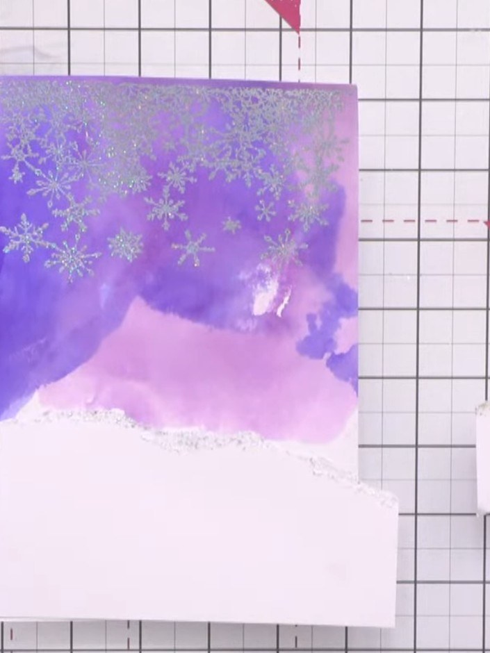 Stap 15: Glue the torn white snow drift pieces to the left edge of the card front. Leave the right edge untrimmed for n