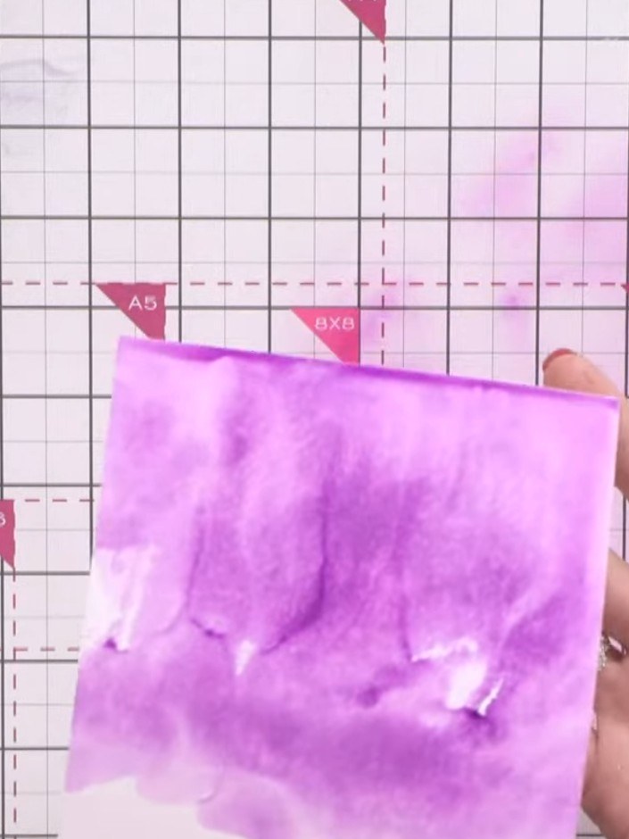 Stap 2: Apply purple ink to another area of the white cardstock. Use a wet brush or water to blend the purple ink, cre