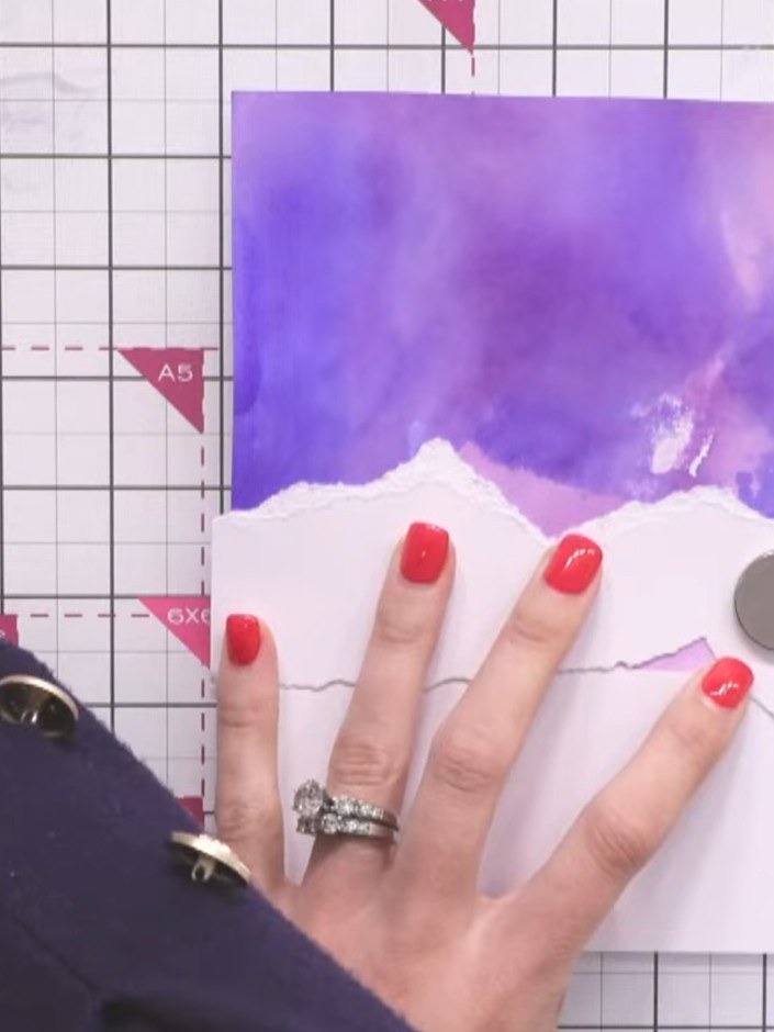 Stap 6: Layer the torn white pieces onto the inked purple background, positioning them across the lower portion to cre