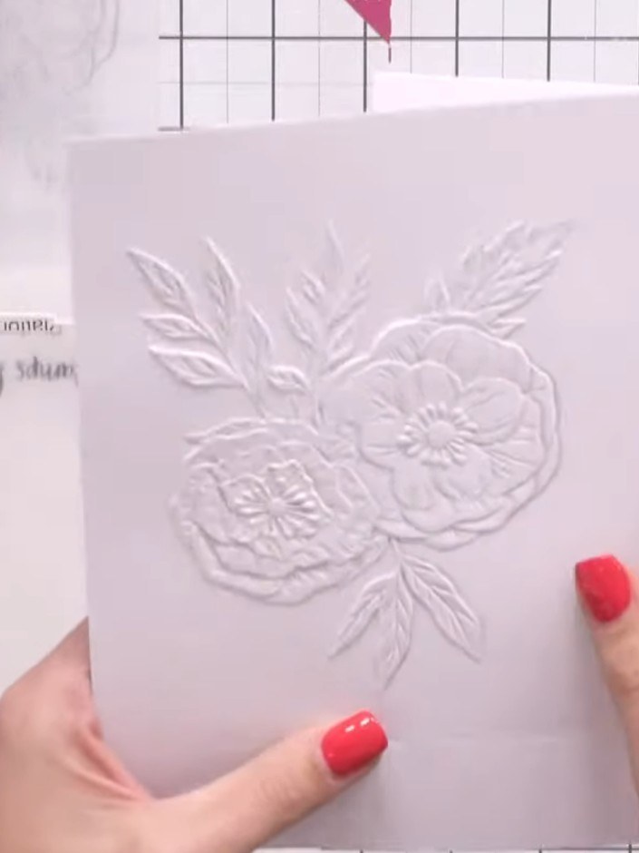 Passo 14: Run the embossed floral panel through a clean embossing folder to add texture to the design. Ensure any ink re